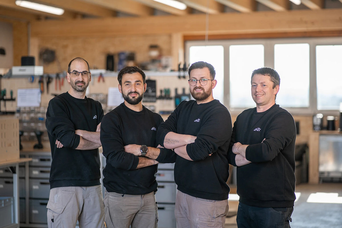 Christoph, Sefa, Fabian und Walter stehen nebeneinander in der Werkstatt