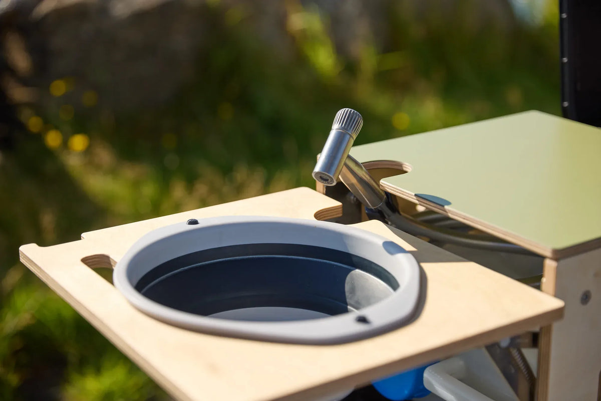 Rundes Faltwaschbecken mit Wasserhahn in der ausziehbaren CampBoks-Waschbeckenablage.