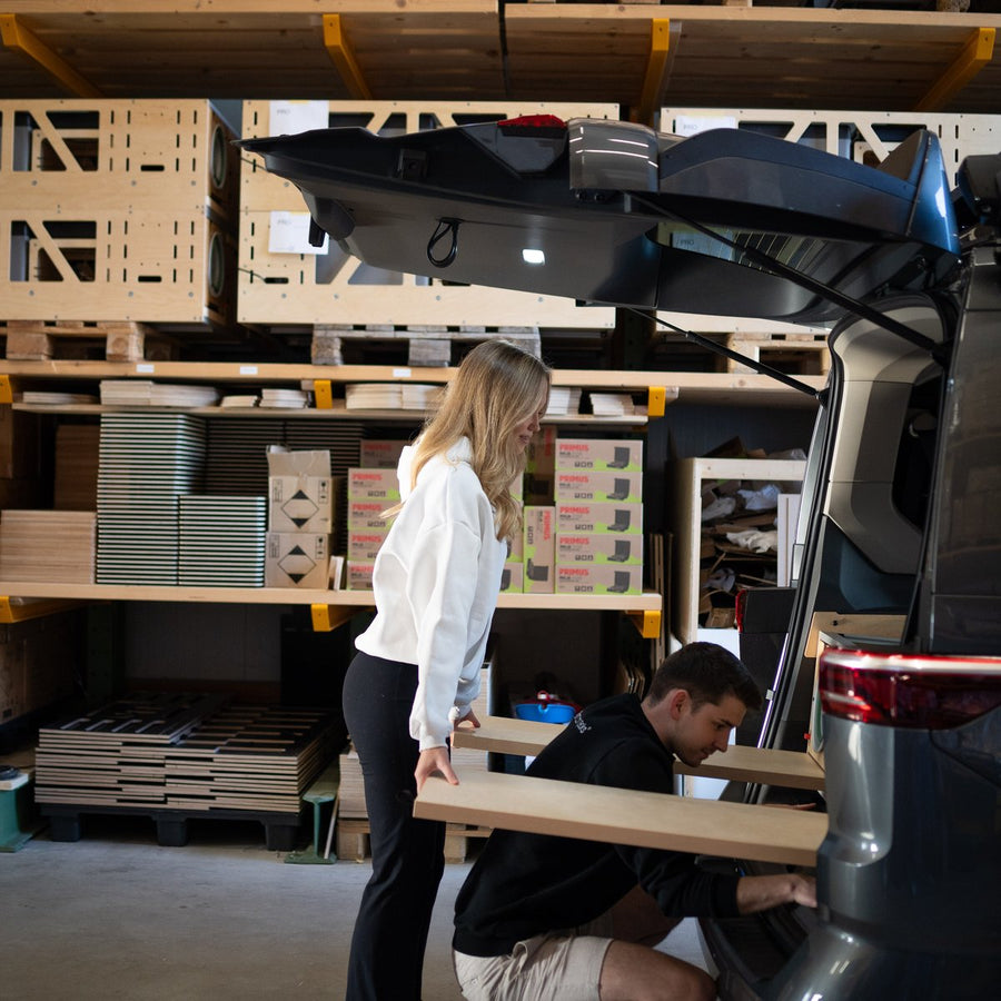 Zwei Personen heben die CampBoks im Lager in das Heck eines Vans